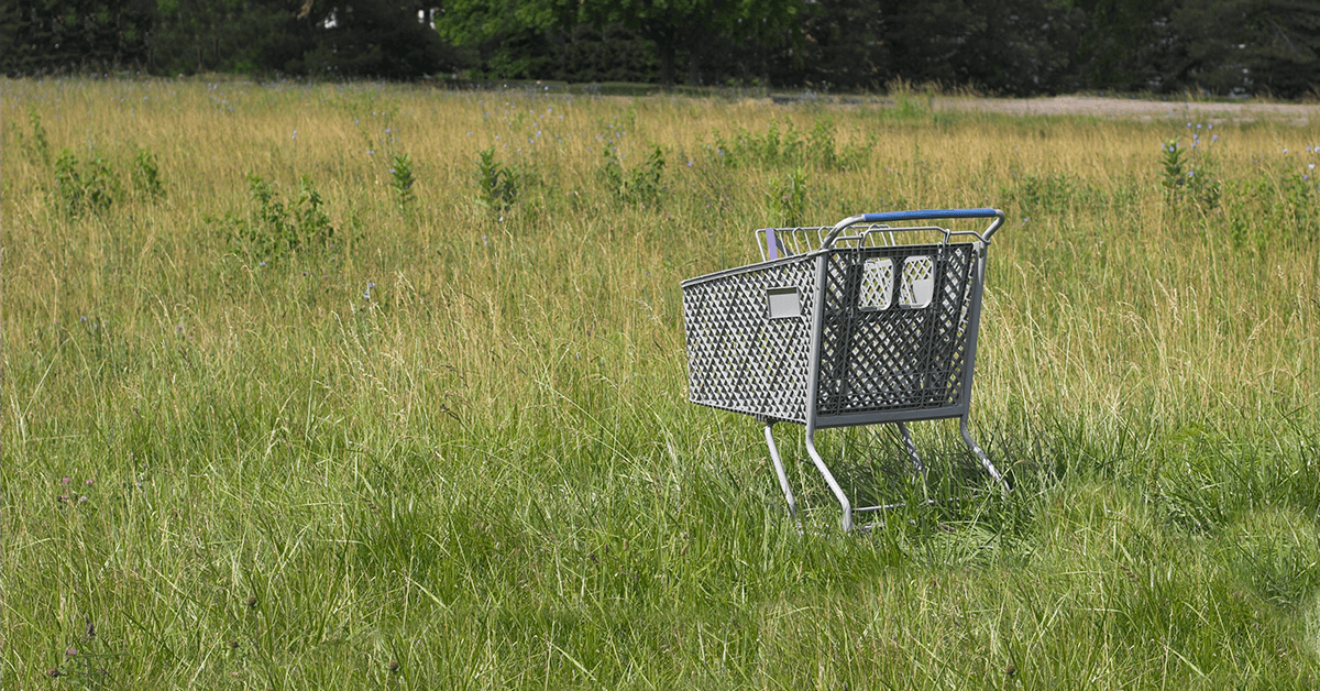 Shopping cart abandoned in a field. 